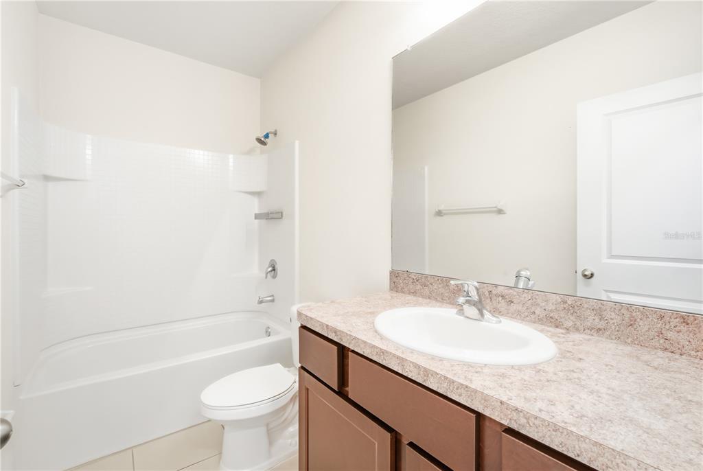 8986 Indigo Trail Loop Riverview, FL 33578 - Photo 17 of 28 a bathroom with a granite countertop sink a toilet a mirror a bathtub and shower