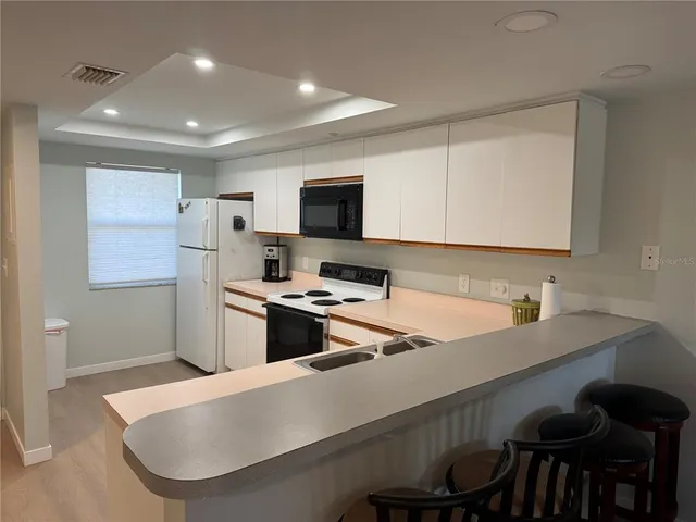 a kitchen with a table chairs a sink dishwasher stove and cabinets