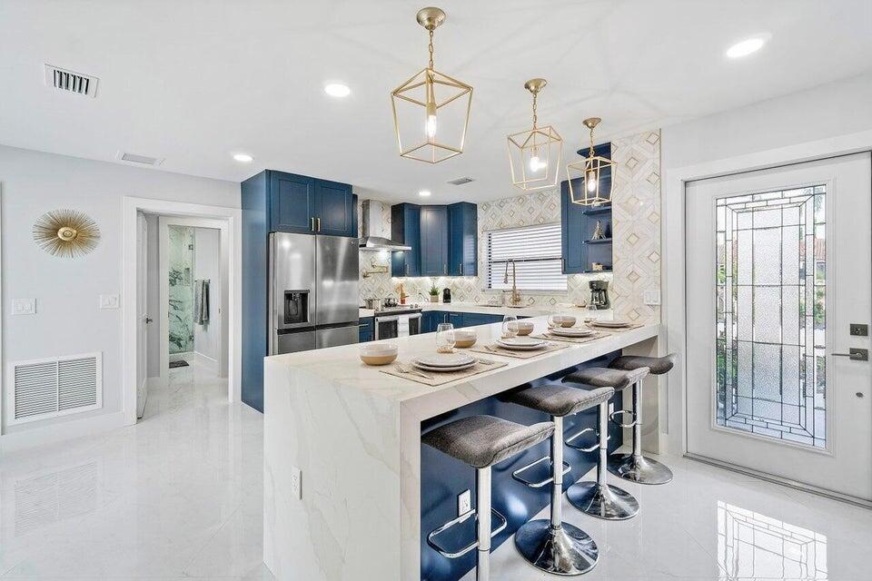 324 Bamboo Road Palm Beach Shores, FL 33404 - Photo 13 of 59 a kitchen with kitchen island a dining table and chairs