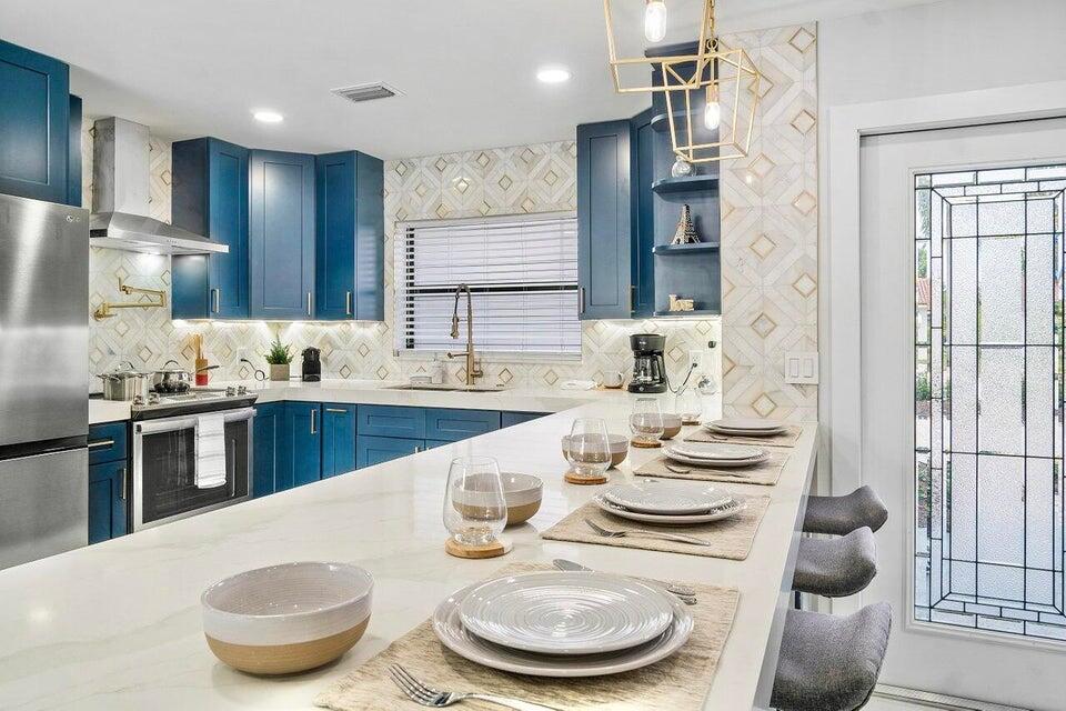 324 Bamboo Road Palm Beach Shores, FL 33404 - Photo 15 of 59 a kitchen with stainless steel appliances kitchen island granite countertop a sink and a refrigerator