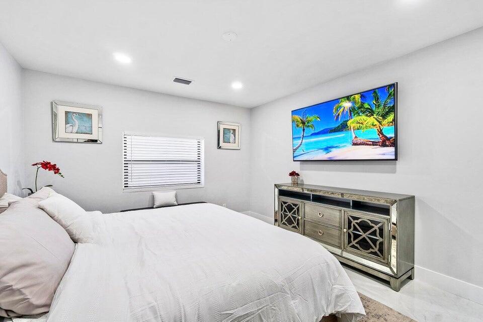 324 Bamboo Road Palm Beach Shores, FL 33404 - Photo 23 of 59 a bedroom with a bed and a flat screen tv