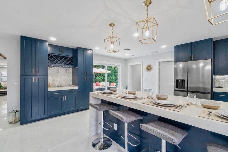324 Bamboo Road Palm Beach Shores, FL 33404 - Photo 3 of 59 a dining room with wooden floor a chandelier fan a wooden table and chairs