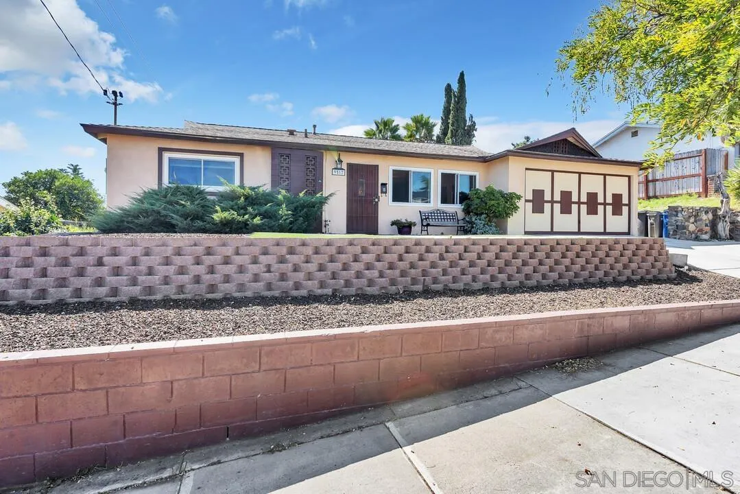 a front view of a house with a yard and potted plants