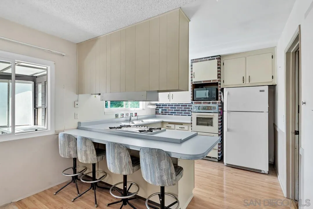 9517 Abbeyfield Road Santee, CA 92071 - Photo 9 of 42 a kitchen with stainless steel appliances granite countertop a dining table chairs a refrigerator and cabinets