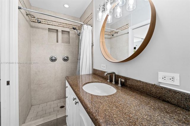 a bathroom with a granite countertop shower a mirror and a sink