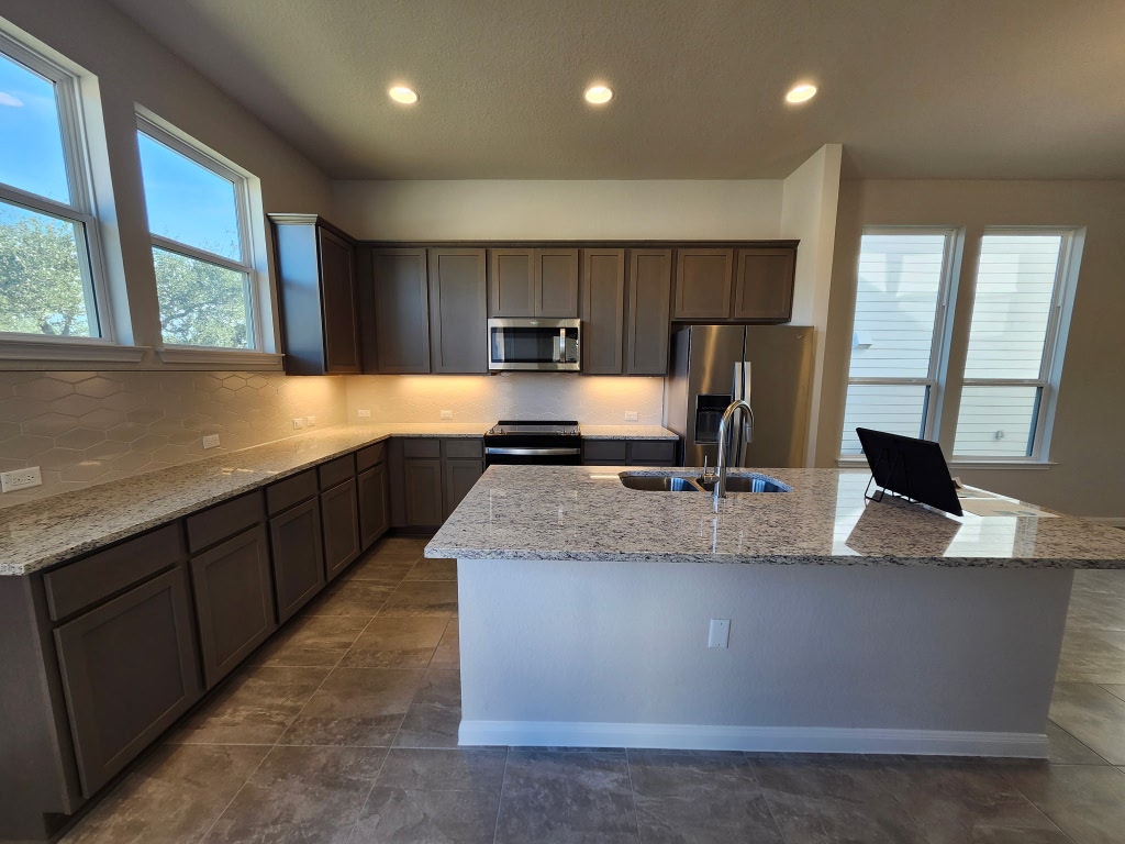 320 Creek Road, Unit 202 Dripping Springs, TX 78620 - Photo 5 of 26 a kitchen with kitchen island granite countertop a sink window and refrigerator