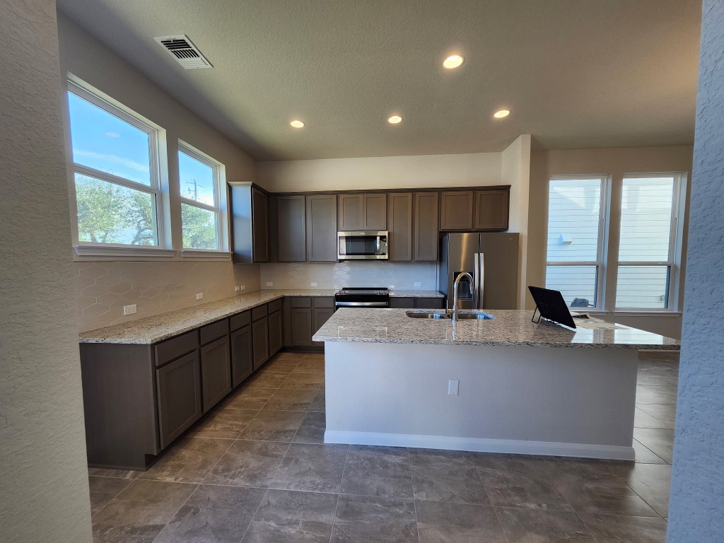 320 Creek Road, Unit 202 Dripping Springs, TX 78620 - Photo 6 of 26 a kitchen with stainless steel appliances granite countertop a sink a stove and a refrigerator