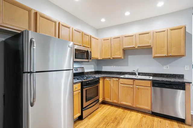 a kitchen with stainless steel appliances a refrigerator a stove a sink cabinets and wooden floor