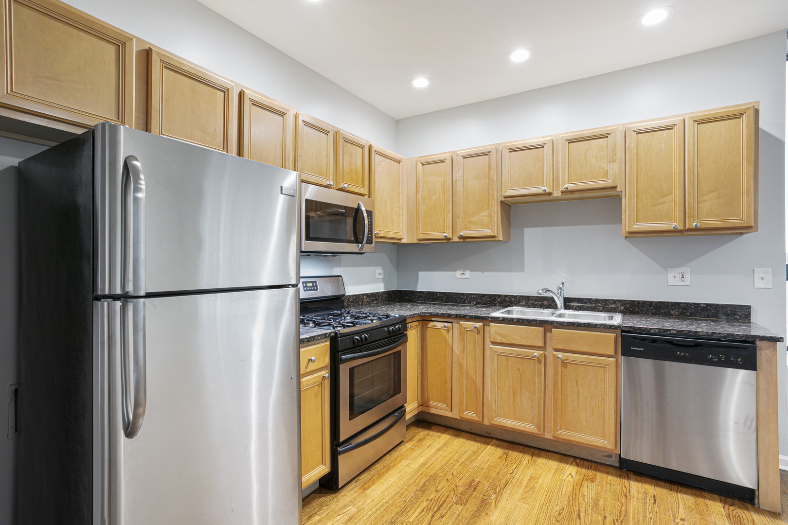 2451 West Howard Street, Unit 401 Chicago, IL 60645 - Photo 5 of 14 a kitchen with stainless steel appliances a refrigerator a stove a sink cabinets and wooden floor