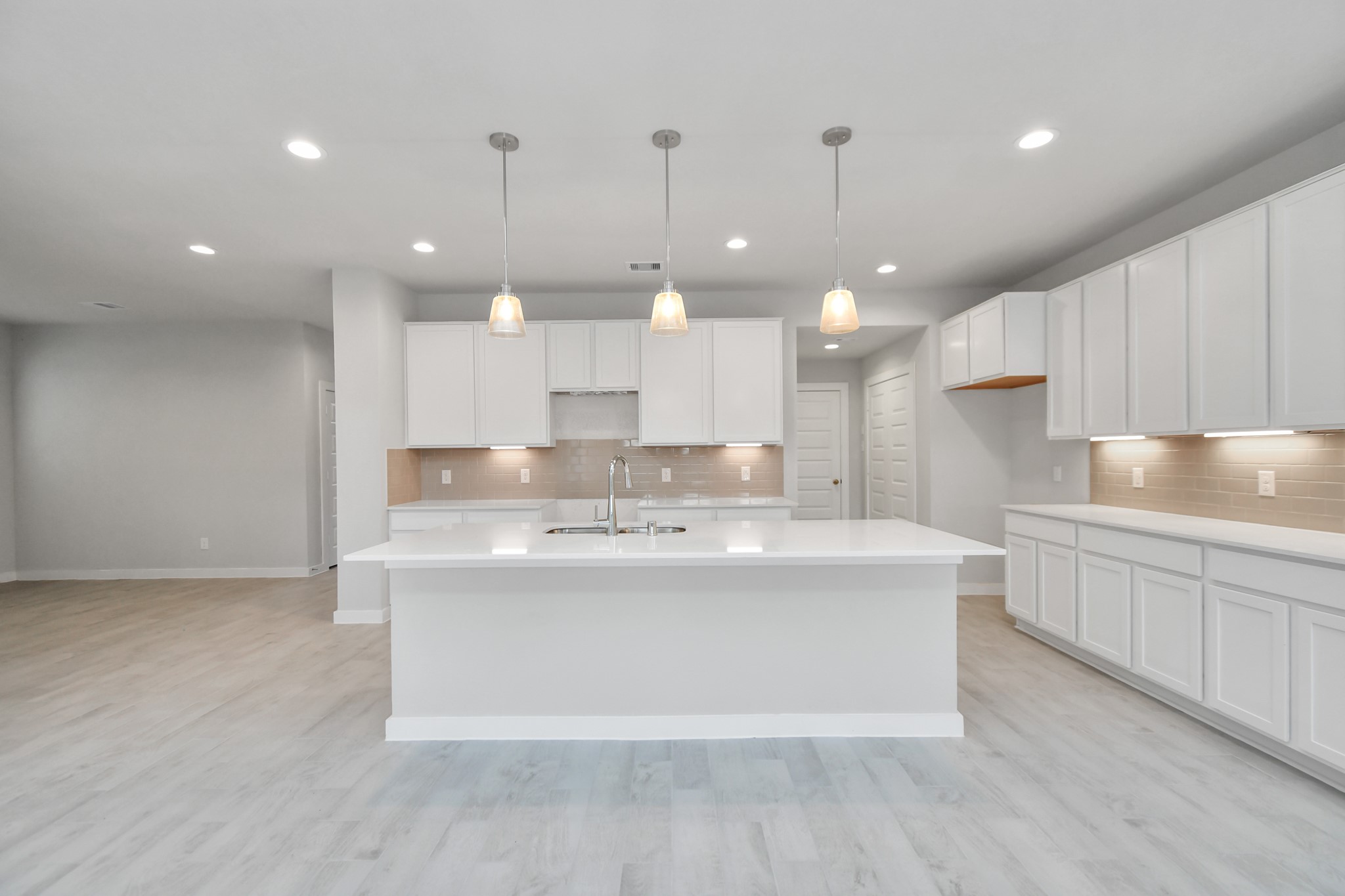 15111 Statice Trail Houston, TX 77044 - Photo 3 of 35 a large kitchen with kitchen island a stove a sink a center island and wooden floor
