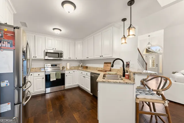 a kitchen with stainless steel appliances granite countertop a refrigerator a sink dishwasher a stove and white countertops with wooden floor