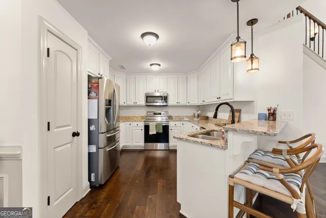 a kitchen with stainless steel appliances granite countertop a refrigerator a stove a sink a dining table and chairs with wooden floor