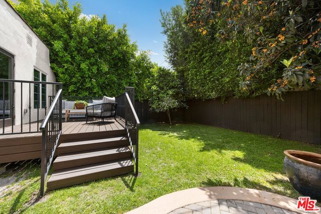 a view of backyard with wooden fence and a large tree