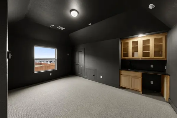 a view of an empty room with a window and a kitchen