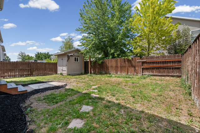 1346 Archmore Drive Springville, UT 84663 - Photo 24 of 32 Enclosed backyard featuring a wood privacy fence, a detached storage shed, a wood-finish deck with steps, and stone paver accents