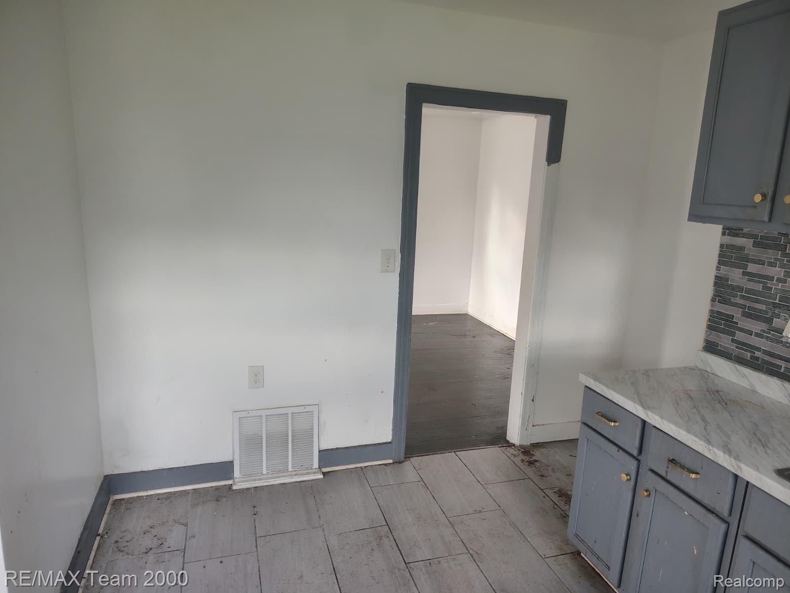 8860 Appoline Street Detroit, MI 48228 - Photo 24 of 45 Kitchen area featuring gray-toned wood-finish flooring, white walls, and a doorway with dark trim