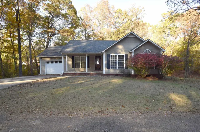 a front view of a house with a garden and trees