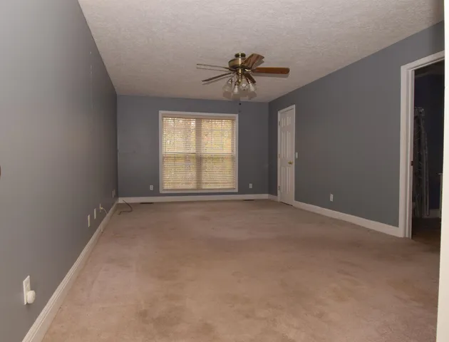 an empty room with windows and chandelier fan