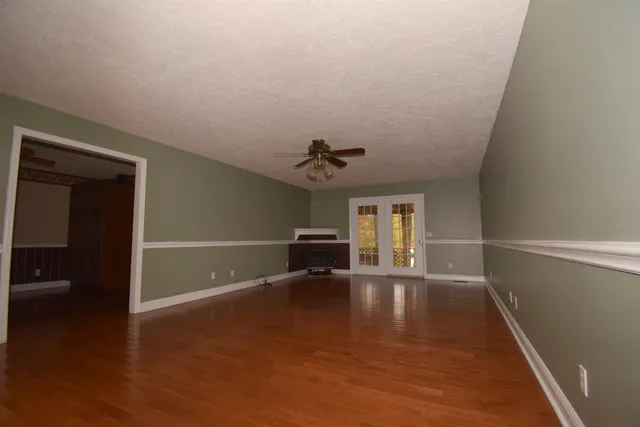 a view of an empty room with window and wooden floor