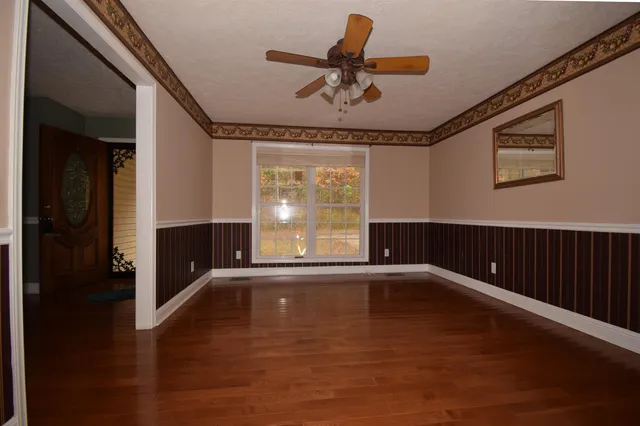a view of empty room with wooden floor and fan