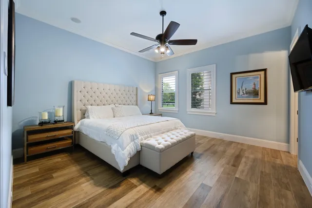 a bedroom with a bed wooden floor and a ceiling fan