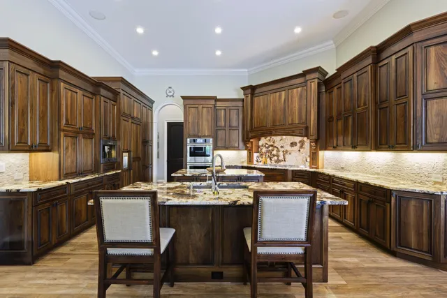 a kitchen with stainless steel appliances granite countertop a table chairs sink refrigerator and cabinets