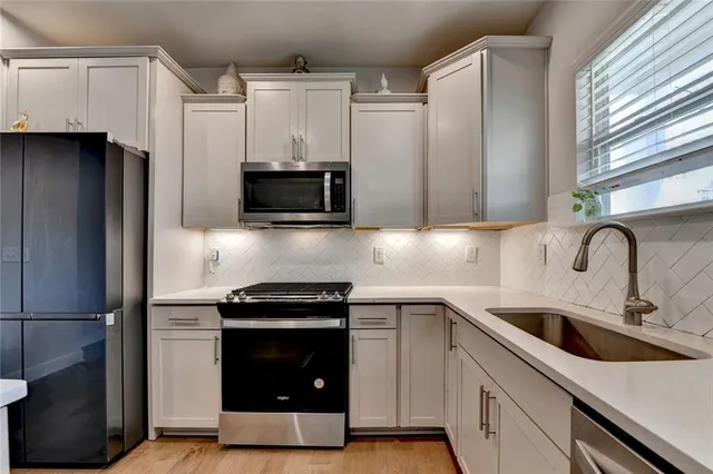 a kitchen with stainless steel appliances a stove a sink a refrigerator and cabinets