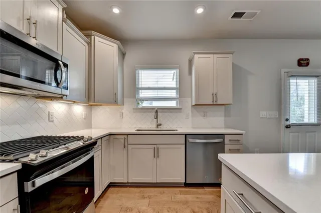 a kitchen with stainless steel appliances a sink stove and cabinets