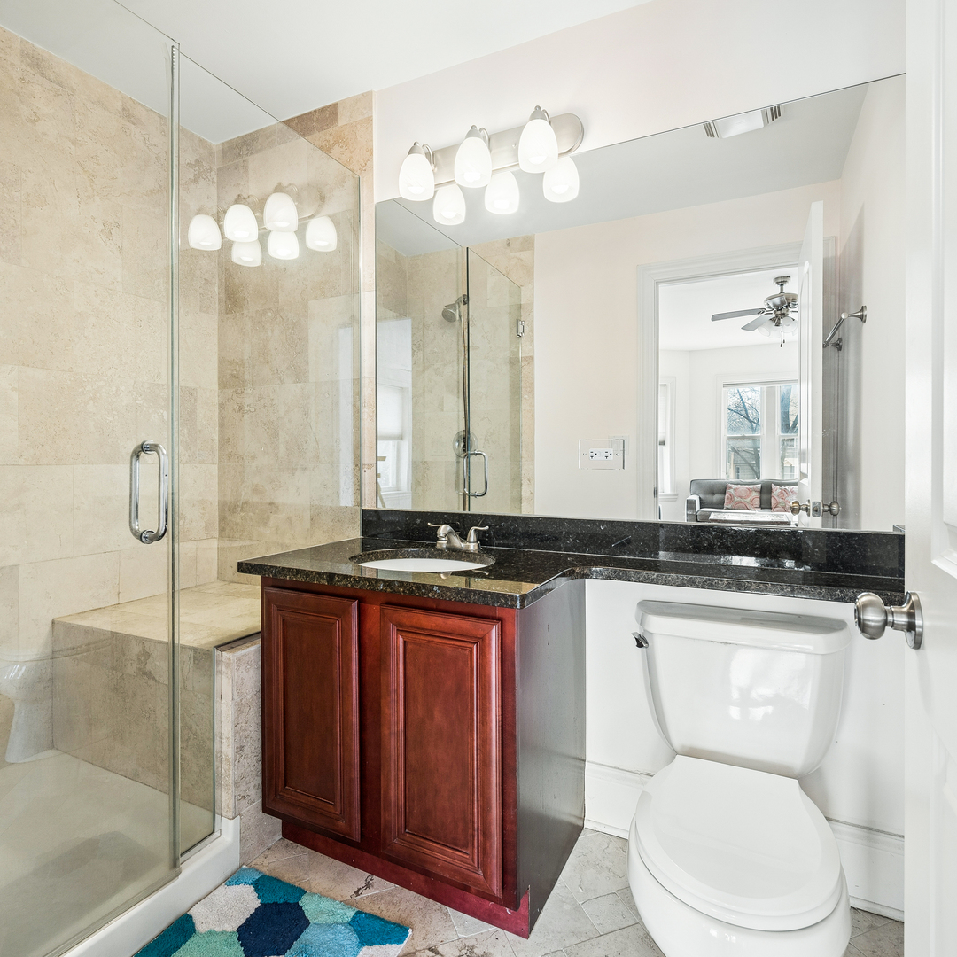 2656 West Lunt Avenue, Unit 1 Chicago, IL 60645 - Photo 11 of 12 a bathroom with a granite countertop sink mirror and toilet