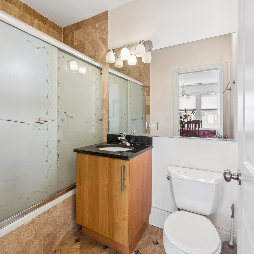 2656 West Lunt Avenue, Unit 1 Chicago, IL 60645 - Photo 12 of 12 a bathroom with a sink a toilet a mirror and shower