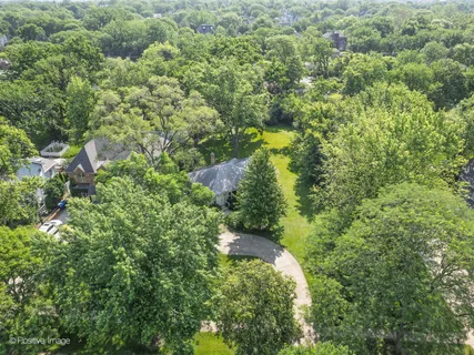 an aerial view of residential house with outdoor space and trees all around
