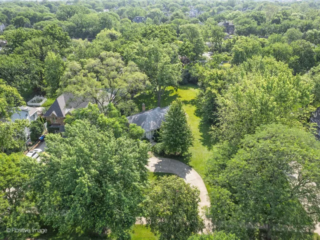 an aerial view of residential house with outdoor space and trees all around