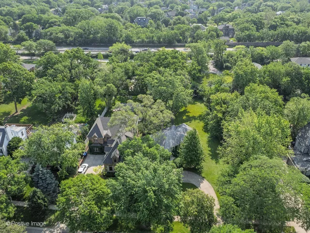 an aerial view of residential house with outdoor space and trees all around