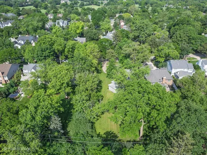 an aerial view of residential house with outdoor space and trees all around