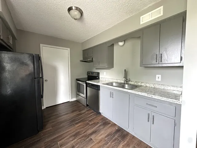 a kitchen with granite countertop a refrigerator sink and cabinets