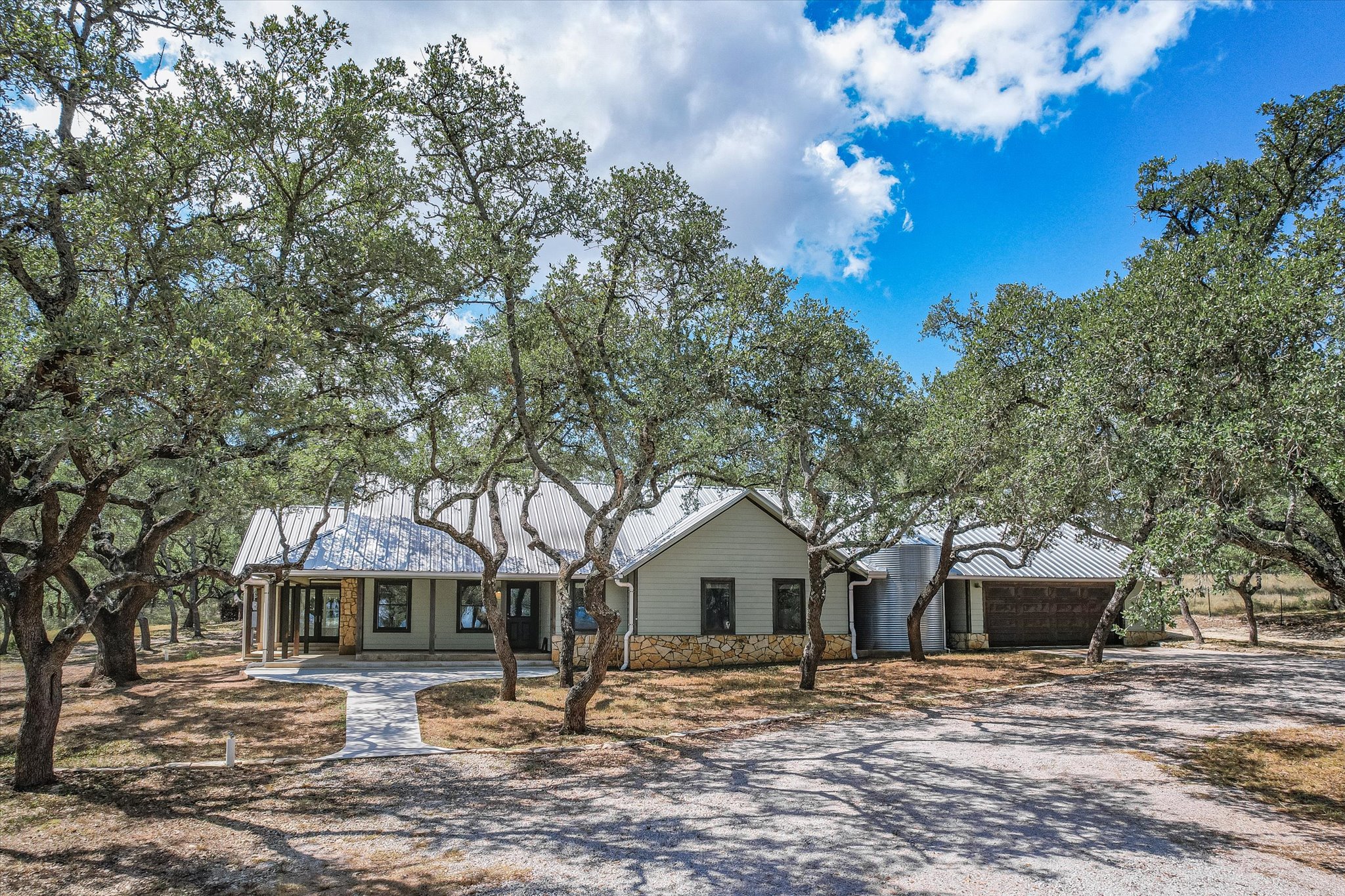 878 Ranch Road 2766 Johnson City, TX 78636 - Photo 6 of 40 a front view of a house with a garden and trees