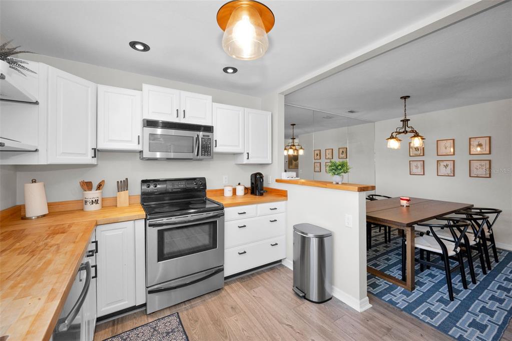 208 Caryl Way Oldsmar, FL 34677 - Photo 7 of 28 a kitchen with stainless steel appliances granite countertop a stove top oven a sink dishwasher and white cabinets with wooden floor