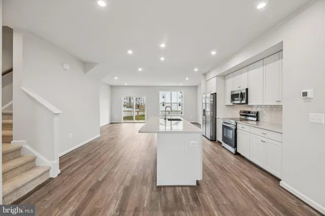 a large kitchen with cabinets wooden floor and stainless steel appliances