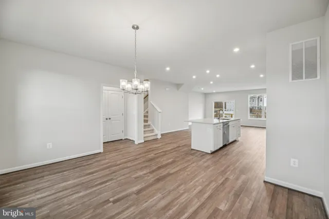 a view of a room with kitchen island stainless steel appliances wooden floor and a chandelier