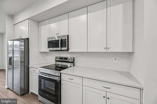 a kitchen with granite countertop white cabinets stainless steel appliances and a sink