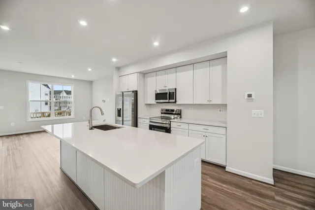 a kitchen with a sink a stove a refrigerator and white cabinets with wooden floor