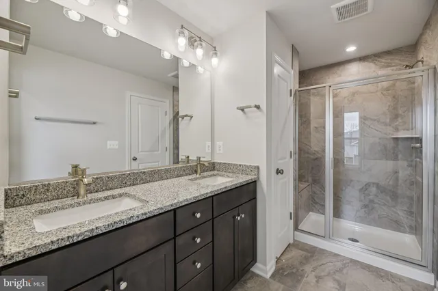 a bathroom with a granite countertop sink mirror and shower