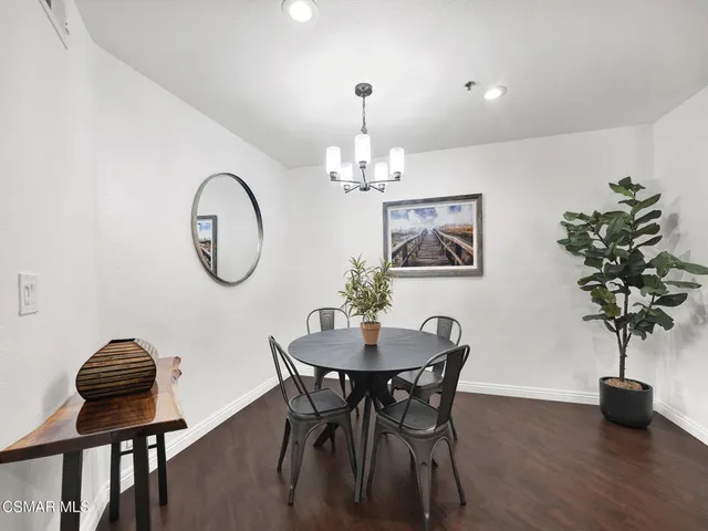 a dining room with wooden floor a chandelier a wooden table and chairs
