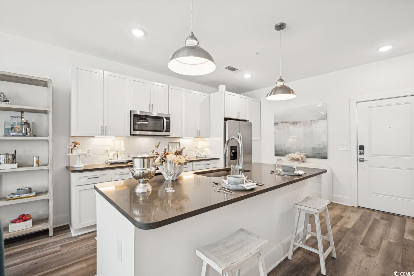 331 Pickwick Drive, Unit A2 Myrtle Beach, SC 29588 - Photo 11 of 39 Kitchen featuring a kitchen breakfast bar, dark hardwood / wood-style flooring, pendant lighting, a kitchen island with sink, and appliances with stainless steel finishes