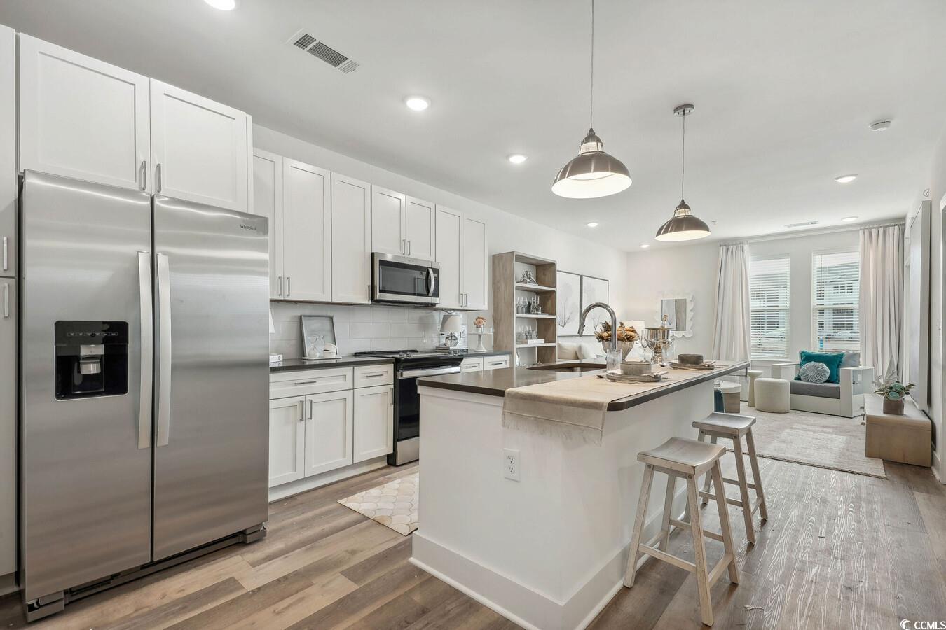331 Pickwick Drive, Unit A2 Myrtle Beach, SC 29588 - Photo 12 of 39 Kitchen with white cabinetry, sink, hanging light fixtures, a kitchen island with sink, and appliances with stainless steel finishes