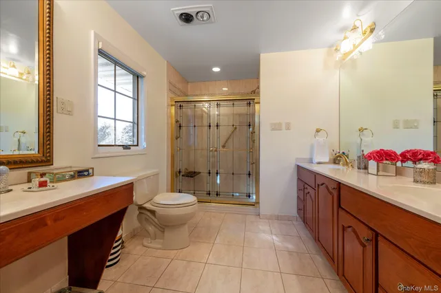 a spacious bathroom with a double vanity sink toilet mirror and shower
