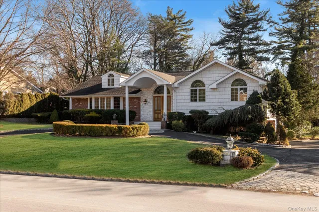 a front view of a house with a garden and trees