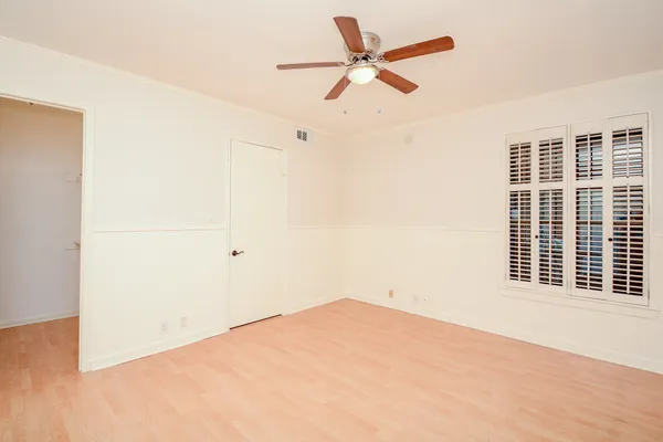 an empty room with a window and a ceiling fan