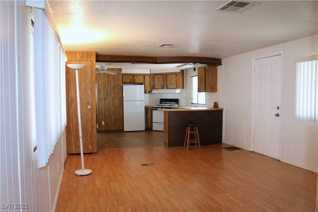 4633 Royal Ridge Boulevard Las Vegas, NV 89103 - Photo 3 of 13 Kitchen with white appliances, visible vents, brown cabinetry, and wood finished floors
