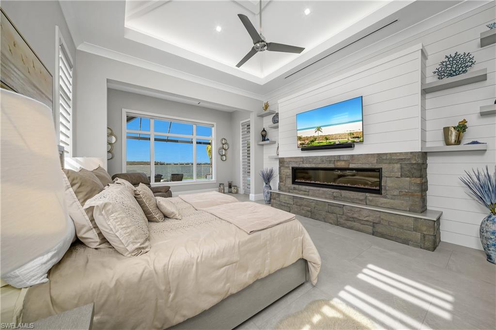 18410 Blue Eye Loop Fort Myers, FL 33913 - Photo 23 of 49 Primary suite with uplight vaulted ceiling, stone fireplace, floating shelves, and separate seating are with stunning views of Wildblue Lake.